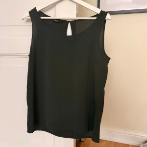 Mörkgrön ärmlös linnetopp från ONLY - Snygg mörkgrön linnetopp från ONLY i storlek 38. Toppen är ärmlös med rund halsringning och har en liten knappdetalj med öppning i ryggen. Materialet är lätt och luftigt, perfekt för varmare dagar. Enkel och stilren design som funkar till många olika looks.