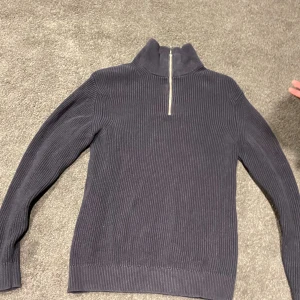 Mörkblå ribbad half zip - Snygg mörkblå halfzip ribbad struktur och half zip framtill. Tröjan har långärmade och en hög krage som ger en cool och stilren look. Perfekt för dig som gillar klassiska och enkla plagg med en twist.