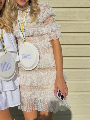 Vit spetsklänning med volanger - Supersöt kort klänning från By Malina i vit spets med volanger och hög krage. Klänningen har korta ärmar, transparent spets och dragkedja i ryggen. Perfekt till student eller sommarens alla tillfällen. Fodrad i beige underton. Ärmarna är omsydda till att vara kortärmade istället för 3 kvarts. Nypris ca 3000kr