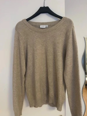 Beige stickad tröja från Vila - En enkel och stilren beige stickad tröja från Vila. Tröjan har rund halsringning, långa ärmar och ribbade muddar vid ärmslut och nederkant. Perfekt att slänga på sig när det är lite kyligare ute.