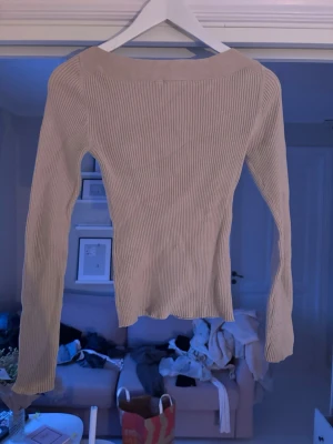 Beige ribbad långärmad tröja - Säljer en beige ribbad långärmad tröja med tight passform. Tröjan har en enkel och stilren design med rund halsringning och är perfekt att matcha med jeans eller kjol. Supermjuk och stretchig, passar både till lager-på-lager och som den är.