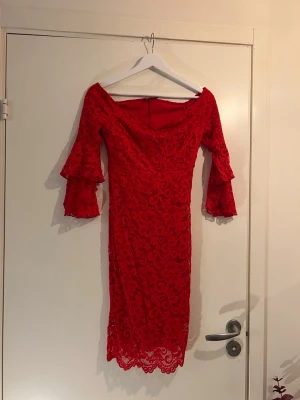 Röd spetsklänning från NLY One XS - Supersnygg röd spetsklänning från NLY One i storlek XS. Klänningen har figurnära passform, v-ringning och trekvartsärm med volangdetaljer. Blommigt spetsmönster och dragkedja bak. Perfekt för dig som vill sticka ut!