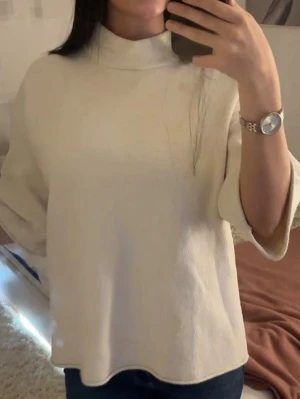 Vit tröja med trekvartsärm - Säljer en stilren vit polotröja med trekvartsärm. Tröjan har en hög krage och en loose passform som ger en avslappnad vibe. 