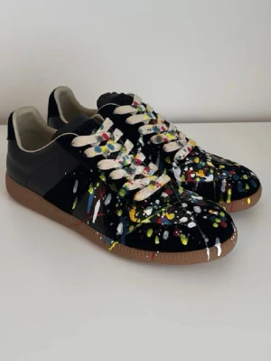 Maison Margiela GATs Paint Edition  - Maison Margiela Paint Splatter sneakers i mycket fint skick. 100 % äkta, inga kopior. Kvitto finns. Fick dem i julklapp men de passade tyvärr inte, därför säljs de vidare. Använda mycket sparsamt.