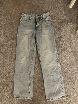 Baggy ljusblå jeans från &Denim - Baggy jeans i ljusblå tvätt från &Denim. Modellen har låg midja och raka ben för en avslappnad vibe. Klassisk femficksdesign och slitna detaljer ger en cool vintagekänsla. Perfekta för dig som gillar loose fit och streetstyle.