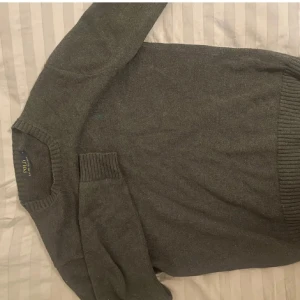 Mörkgrå stickad tröja Polo Ralph Lauren - Mörkgrå stickad tröja från Polo Ralph Lauren i storlek S. Klassisk rund hals och ribbade muddar vid ärmslut och nederkant. Perfekt för dig som gillar stilrena och tidlösa plagg med diskret logga på bröstet.