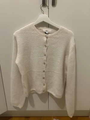 Vit kofta från Gina Tricot - Supermjuk kofta från Gina Tricot i alpackablandning. Klassisk rund hals, långa ärmar och knäppning med pärlemorknappar framtill. Helt oanvänd med lappen kvar. Anledningen att jag säljer är eftersom jag köpte fel storlek och sedan glömde returnera innan sista datumet. 😊💓