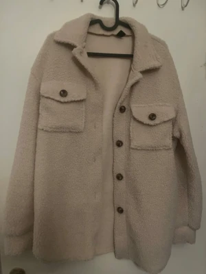 Beige teddy jacka strl XS - Nästintill oanvänd. Mysig beige teddyjacka med stora bröstfickor och knappar framtill. Perfekt för lager på lager och ger en chill vibe till din outfit. 🧥 (kan funka för strl S också)  