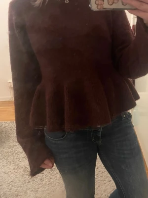 Mörkröd stickad tröja Gina Tricot - Mysig mörkröd stickad tröja från Gina Tricot i storlek XS. Tröjan har lång ärm, rund hals och en volangliknande peplum nedtill som ger en snygg siluett. Perfekt till jeans eller kjol för en trendig look.