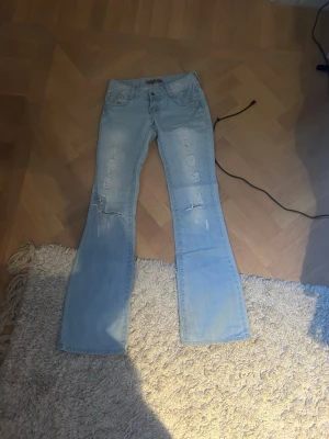 Ljusblå bootcut jeans med slitningar - KAN TÄNKA MIG FÖRHANFLA OM PRIS!!Säljer ett par ljusblå bootcut jeans från Replay med snygga slitningar framtill. Jeansen har klassisk femficksdesign, låg midja och är tillverkade i mjukt denimtyg. Det är så snygga och skulle säga att det passar någon som är 165-173 i längd 