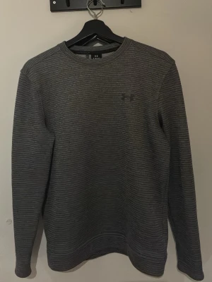 Grå randig tröja från Under Armour Golf  - Säljer en grå långärmad tröja från Under armour. Golf tröja som passar bra till kyligare golf dagar. 