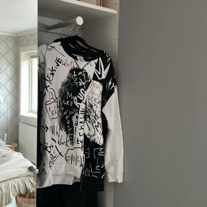 Cruella De Vil svartvit sweatshirt - Säljer en svartvit långärmad sweatshirt från Cruella De Vil-kollektionen. Tröjan har coolt grafitti-inspirerat tryck med text och illustrationer på framsidan, samt broderad logga i nacken. Materialet är mjuk bomull och passformen är normal. 🍷