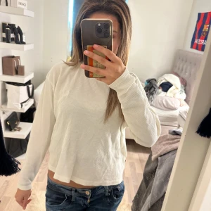 Vit ribbad långärmad tröja - Säljer en vit långärmad tröja med ribbad struktur. Tröjan har en avslappnad passform och rund halsringning, perfekt för en chill och enkel stil. Passar till jeans eller kjol för en clean look.