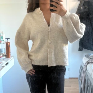 Beige kofta puffärm - Supermjuk beige kofta från Dazy med puffiga ärmar.Storlek S, den har tre svarta fläckar på insidan som ej syns när den är på, de går säkert att ta bort, har inte försökt.