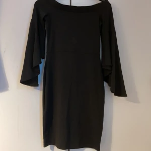 Svart klänning med vida ärmar Gina tricot  - Priset kan diskuteras. En svart, stilren klänning med vida, långa ärmar och rak passform. Klänningen har en enkel design med båtringad hals och slutar ovanför knäna. Perfekt för dig som gillar minimalistisk och elegant stil.