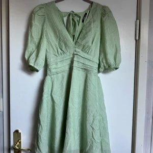 Ljusgrön kort klänning med puffärm - Superfin ljusgrön kort klänning från Gina Tricot  med v-ringning, puffärmar och knytning i ryggen. Klänningen har smock i midjan baktill. Perfekt för vår och sommar!
