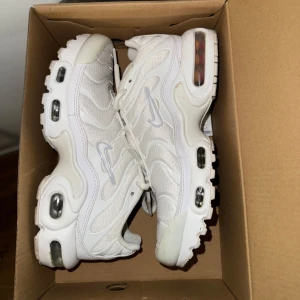 Nike Air Max plus - Säljer ett par fräscha vita Nike Air Max sneakers med synliga luftbubblor i sulan och coola vågformade detaljer på ovandelen. Skorna har snörning och är tillverkade i syntet och mesh för en sportig vibe. Perfekta för dig som gillar streetstyle och vill ha bekväma skor med snygg design. Använda några gånger, inga skador.