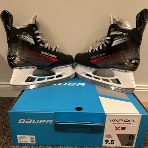 Bauer Vapor X3 hockeyskridskor 9.5 - Säljer ett par Bauer Vapor X3 hockeyskridskor i storlek 9.5. Skridskorna har svart och silver design med röda detaljer, snörning och vit sula. Yttermaterialet är syntet med robust känsla och innersidan är vadderad för extra komfort. Perfekta för dig som vill ha snabba fötter på isen. De är använda en säsong och därför i väldigt fint skick. Frakt ingår ej💕