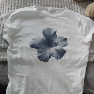 Vit t-shirt med blå blomma - HAR FLER SUBDUED TRÖJOR UPPLADDADE‼️‼️‼️Vit t-shirt från Selected med en stor blå blomma tryckt på framsidan. Klassisk rund halsringning och korta ärmar. Perfekt för dig som gillar stilrena plagg med en twist.