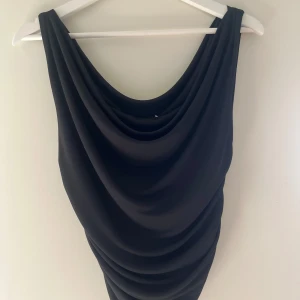 Svart draperad topp från Cubus - Säljer en svart topp från Cubus i storlek S. Toppen har en snygg draperad design med mjukt fall och är ärmlös. Aldrig använd🩷