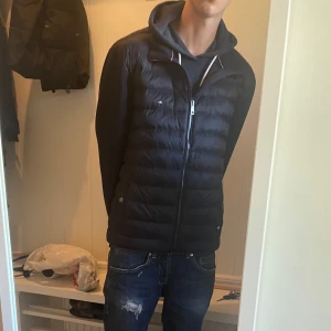Tommy Hilfiger mörkblå pufferjacka - Helt ny mörkblå Cardigan från Tommy Hilfiger som är oanvänd för 2400kr. Jackan har dragkedja, ståkrage och stilrena logodetaljer. Materialmix med polyester och bomull, perfekt för dig som är Grisch och letar efter en fet cardigan. 