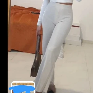 Vita vida byxor med hög midja - Snygga vita byxor med hög midja och utsvängda ben. Byxorna har en clean look utan synliga detaljer och är tillverkade i ett stretchigt, mjukt material som sitter skönt på kroppen. Perfekta för en trendig och stilren outfit.