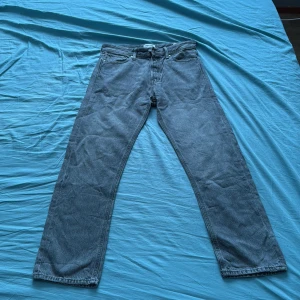 Gråa jeans Jack & Jones Relaxed Chris - Säljer ett par gråa jeans från Jack & Jones, modell Relaxed Chris. Jeansen har en avslappnad passform med raka ben och klassisk femficksdesign. Tillverkade i denim och läderpatch bak i midjan. Perfekta för en chill och stilren look. Storlek 30/32