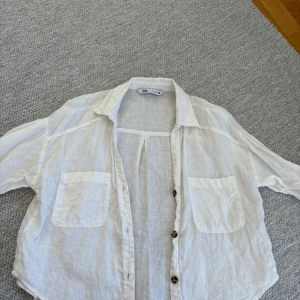 Vit linneskjorta från Zara - Vit skjorta från Zara i luftig linnemix med två bröstfickor och snygga knappar framtill. Skjortan har klassisk krage och lång ärm, perfekt för en chill och stilren look.
