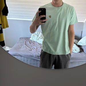 Mintgrön t-shirt från Lyle & Scott - Fräsch mintgrön t-shirt från Lyle & Scott med klassisk gul logga på bröstet. T-shirten har rund hals, korta ärmar och är gjord i mjuk bomull. Perfekt för dig som gillar stilrena och cleana plagg med en touch av street.