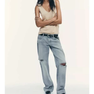 Ljusblå baggy jeans med slitningar - Säljer ett par ljusblå baggy jeans med slitna detaljer på båda knäna.  Säljs för de inte sitter som jag vill, skulle säga att de är lite mindre i storlek, har endast hunnit använda typ en gång