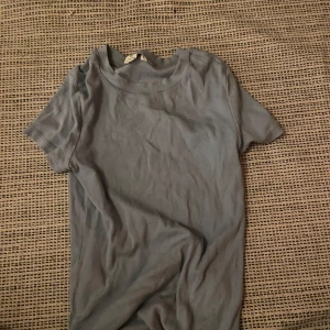 Ljusblå ribbad t-shirt från Monki - Säljer en ljusblå ribbad t-shirt från Monki i storlek XXS. T-shirten har korta ärmar och en klassisk rund halsringning. Perfekt för dig som gillar en enkel och stilren look med lite extra struktur tack vare det ribbade materialet.