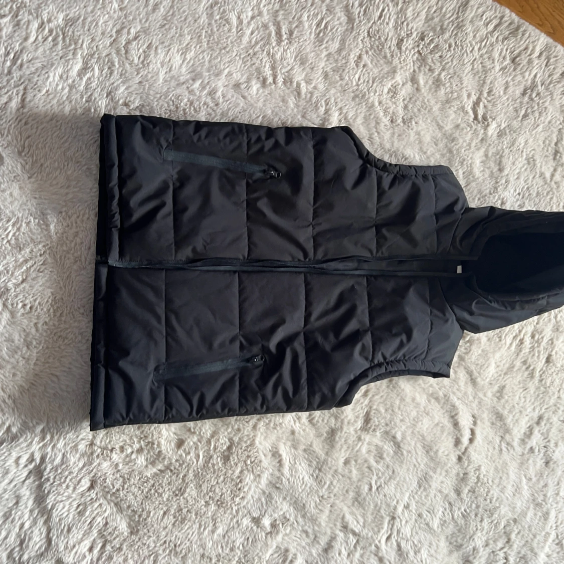 Svart dunväst med huva och dragkedja