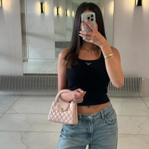 Svart croppad linnetopp från Prada - Säljer en svart croppad linnetopp från Prada med diskret logga framtill. Toppen har en tight passform så är mer som en XS men jag som är S har kunnat ha den 