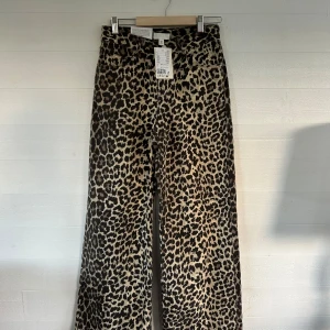 Leopardmönstrade jeans - Säljer ett par leopardmönstrade jeans från H&M i storlek 34. Byxorna har hög midja, raka ben och coolt djurmönster i beige och svart. Materialet är mjukt och ger en trendig vibe. Perfekta för dig som vill sticka ut med din stil.🤩💕