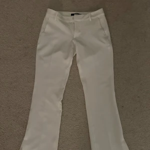 Vita bootcut kostymbyxor från BikBok - Snygga vita kostymbyxor från BikBok i storlek 34. De är nästan aldrig använda så de är i nyskick! De har en slits längst ner.