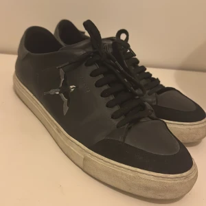 Axel Arigato Clean 90 Bee Bird Sneaker Black - Svarta sneakers från Axel Arigato i skinn med broderad fågel på sidan och vit sula. Klassisk låg modell med svarta snören och diskret logga på hälen. Tydligt använda. Putsa och tvätta, blir som nya! Nypris: 2599kr Pris: 700kr. Pris kan diskuteras!! Kvitto samt påse följer med!