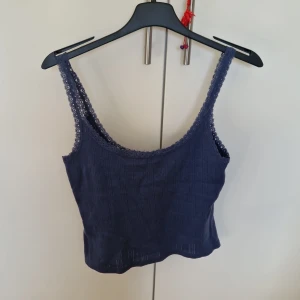 Mörkblå ribbad linnetopp med spets - Supersöt mörkblå linnetopp från 157 i ribbad bomull med tunna axelband och spetskant runt halsringning och axelband.