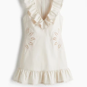 Vit kortklänning med volang och spets - Supersöt vit kortklänning med volang vid halsringningen och nederdelen. Klänningen har broderade spetsdetaljer i blommönster på sidorna och är ärmlös med djup v-ringning. Perfekt för sommarens alla tillfällen! Och så trendig och gullig! Orginalpris 599! Aldrig använd så den ej passar mig 