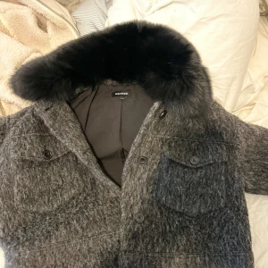 Grå pälsjacka från Meotine S/M - Säljer en jättefin grå pälsjacka från Meotine med fluffig svart krage, storlek l/xl, men den är liten i storleken så passar mig jättebra som har S, även M. Skön nu till hösten och vintern!