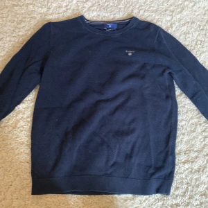 Mörkblå bomullströja från Gant - Snygg mörkblå tröja från Gant i premium bomull. Klassisk rund halsringning, diskret Gant-logga på bröstet och ribbade muddar. Perfekt för dig som gillar stilrena och tidlösa plagg. Långärmad och i normal passform.
