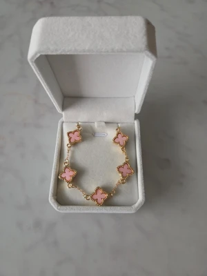 Armband med rosa klöver - Ett vackert armband med rosa klöverdetaljer. Perfekt för att addera en touch av elegans till din stil.