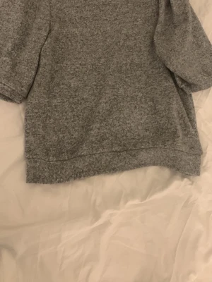 Grå loose sweatshirt med kort ärm - Mysig grå sweatshirt med loose passform och korta ärmar. Perfekt för chill dagar och enkel att matcha med jeans eller mjukisbyxor. Materialet känns mjukt och har en melerad look. Snygg och enkel stil för dig som gillar bekväma tröjor.
