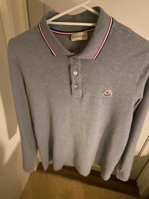 Moncler pikéskjorta - Snygg pikétröja från Moncler. Självklart äkta vara. Storlek L men tröjan är lite mindre I storlek så passar bättre den som bär S/M. 