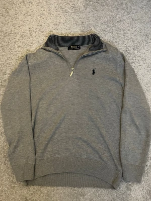 half zip tröja från Polo Ralph Lauren - Säljer en grå långärmad tröja från Polo Ralph Lauren med half zip. Kragen har snygga marinblå på insidan. Perfekt för chill höst och vinterdagar. Knappt använd och är i helt nytt skick