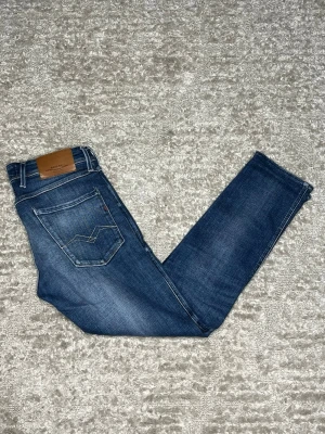 Replay Anbass - Hej jag säljer ett par Replay Anbass hyperflex. Jeansen i riktigt snygg blå färg med slitningar perfekt för dig som vill ha ett par kvalitetsjeans med grym passform. Nypris ≈2000kr, mitt pris 599kr.  Skick: 9/10 Storlek: W31L32 Midja: 39cm Lår: 24cm Ytterlängd: 93cm Innerlängd: 70cm  Skriv gärna om du vill ha fler bilder eller har frågor!
