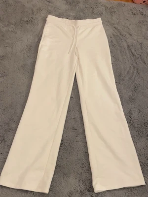 Vita mjukisbyxor med snörning - Säljer ett par vita mjukisbyxor med breda ben och snörning i midjan. Byxorna har en relaxed passform och är gjorda i mjukt bomullsmaterial, perfekta för chill dagar. Färgen är helvit och modellen är normal med hög midja. Kan eventuellt tänka mig gå ner i pris