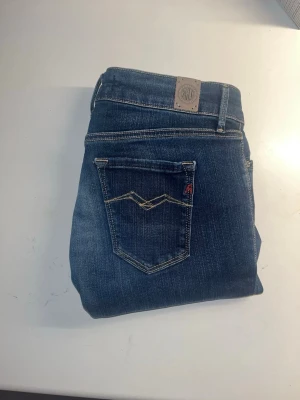 Replay jeans  - Snygga Replay Anbass jeans i mörkblå tvätt och kontrastsömmar. Modellen är slim och har en modern skinny passform med låg midja. Materialet är stretchigt jeans för extra komfort. Midja 32cm, längd 84cm. OBS Längdmåttet saknas men jag uppskattar storleken till L28, men utgå från måtten. JAG SKICKAR EJ FLER BILDER NÄR JAG BÄR JEANSEN! för storleksguide hänvisar jag till måtten och för bättre inblick i passformen rekommenderar jag att googla på modellnamnet. kolla måtten noggrant :) s5,1