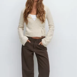 Beige stilren kofta med knyt - Superfin beige kofta med knyt i sidan och långa ärmar. Koftan har en lätt v-uringning med en enkel och stilren design som är lätt att matcha.                                                                   