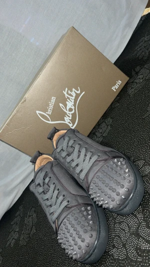 Grå sneakers från Christian Louboutin - Christian Louboutin Grå Sneakers – exklusiv stil med ikonisk röd sula. Perfekta för vardag & fest!