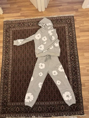 Grå denim tears tracksuit - Säljer en grå Denim Tears tracksuit som är helt ny och oanvänd. Köpt nyligen men säljs på grund av att den är för stor. Väldigt snygg och bekväm passform med hög kvalitet och stilren design. Perfekt för både vardag och streetwear.